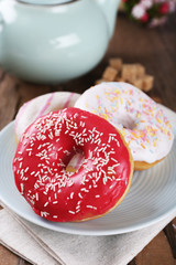 Delicious donuts with icing on plate on table close up