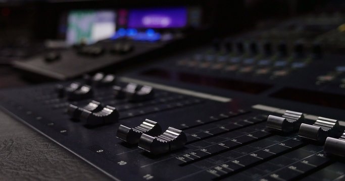 Footage of an audio mixer in a studio, the automatic knobs moving up and down