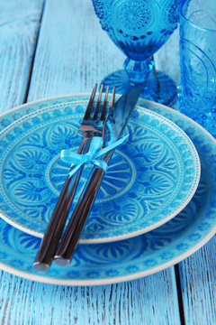 Empty colorful plate, glasses and silverware set on wooden