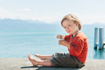 Outdoor portrait of adorable toddler boy eating ice cream