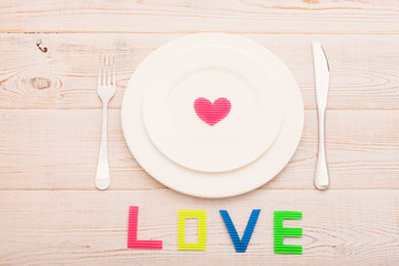 Plate and cutlery on wooden background. Word love.Valentines Day