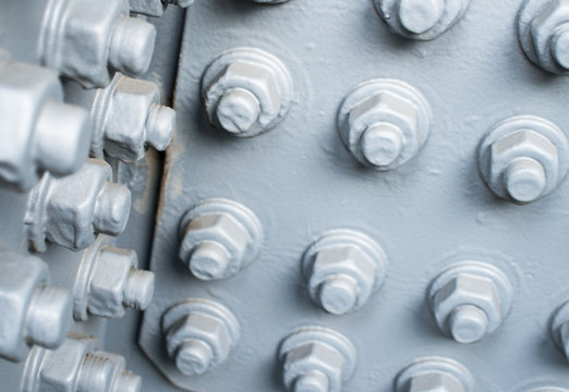 Gray painted metal surface with bolts and nuts