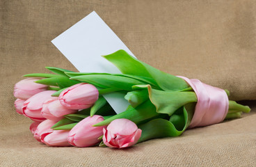 A bouquet of pink tulips with pink satin ribbon and envelope