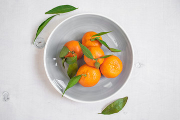 Tangerines with green leaves on white wooden background. Vertica