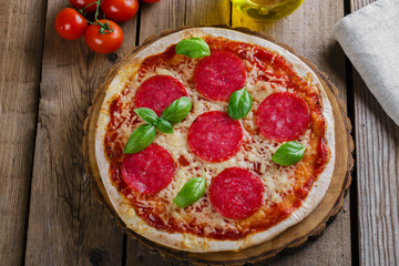pizza with salami round on a wooden surface