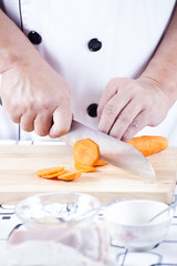 Chef cutting carrot on wooden broad