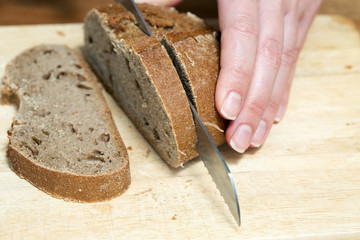 A hand cutting a rye bread