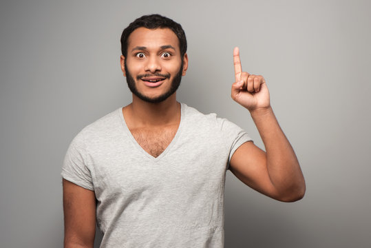 Cheerful mixed race man pointing up