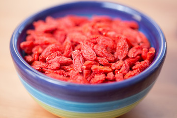 Dried goji berries in colored bowl on wooden table