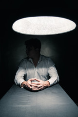 Man in a dark room illuminated only by lamp - obrazy, fototapety, plakaty