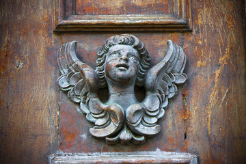 Sculpture of an angel on a wooden door in Italy