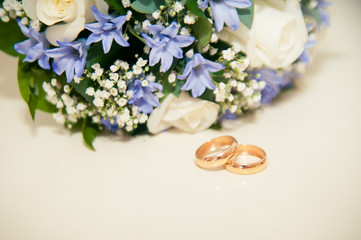wedding rings on a white background with a bouquet of blue ribbo