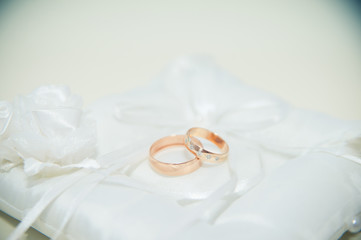Two gold wedding rings lying on the white pillow