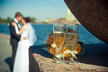 two glasses with champagne and a bouquet of roses on a backgroun