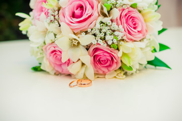wedding rings on a white background with a bouquet