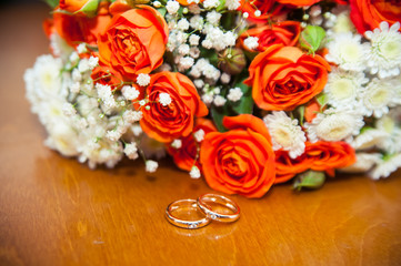 wedding rings on a white background with a bouquet