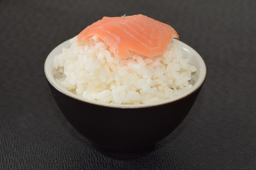 Sushi with salmon in a bowl on a black background.