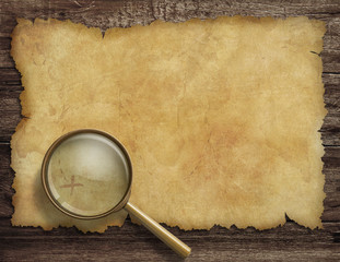 old treasure map on wooden desk with magnifying glass