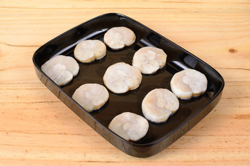 Fresh scallops in a black tray.