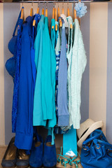 Dressing closet with blue clothes arranged on hangers