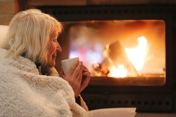 Senior woman relaxing at by fireplace