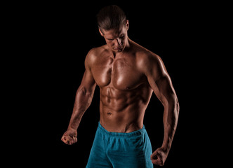 Obraz na płótnie Canvas Handsome muscular bodybuilder posing over black background.