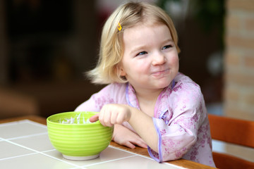 Little girl enjoying muesli with yogurt for breakfast