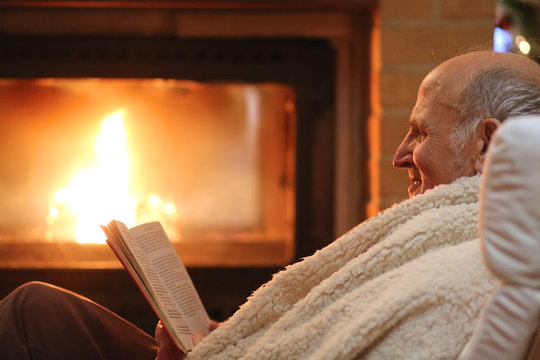 Senior Woman Relaxing At By Fireplace