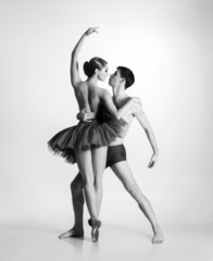 Couple of young and athletic ballet dancers on grey