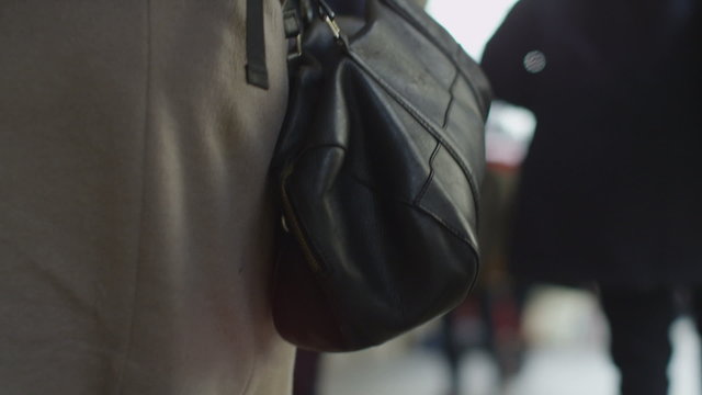 Woman's handbag on display as she walks in front of camera