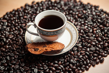 Cup of coffee with cracker on coffee beans