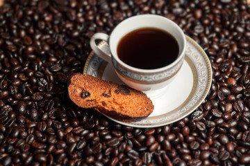 Cup of coffee with cracker on coffee beans