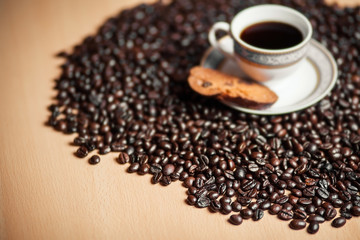 Cup of coffee with cracker on coffee beans
