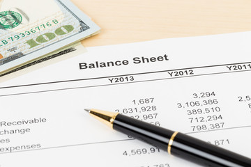 Balance sheet financial report with pen, and banknote