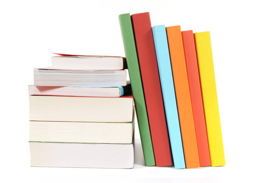 Collection of colorful paperback books in a row line with small stack isolated white background photo