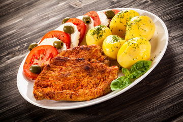 Fried pork chops, boiled potatoes and caprese salad
