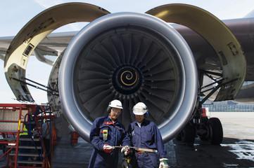 airplane mechanics in front of jumbo jet engine