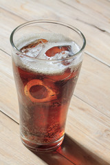 glass of cola with ice on wood