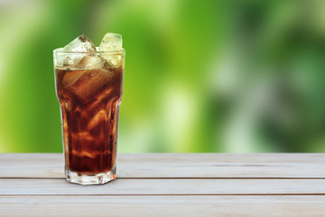 glass of cola with ice on wood