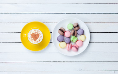Cappuccino with heart shape symbol and macaron