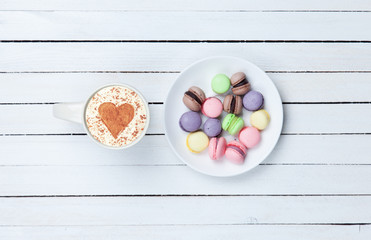 Cappuccino with heart shape symbol and macaron