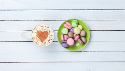 Cappuccino with heart shape symbol and macaron