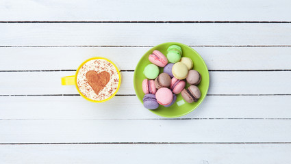 Cappuccino with heart shape symbol and macaron