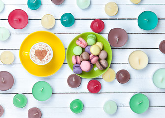 Cup of Cappuccino and candles with macarons