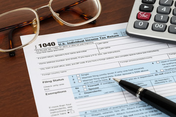 Tax form with pen, glasses, and calculator taxation concept