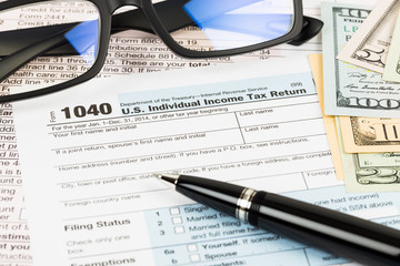 Tax form with glasses, pen, and banknote taxation concept