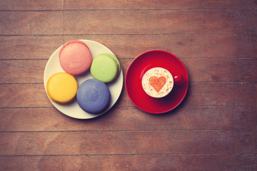 Cup and macarons on wooden background