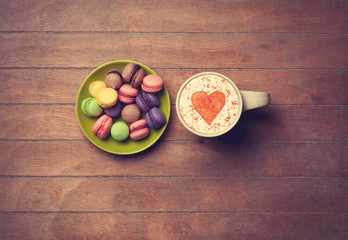 Cup and macarons on wooden background