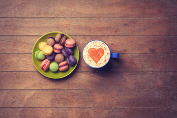 Cup and macarons on wooden background