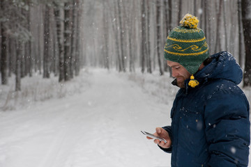 Fototapeta na wymiar Man with smart phone in hand on winter forest